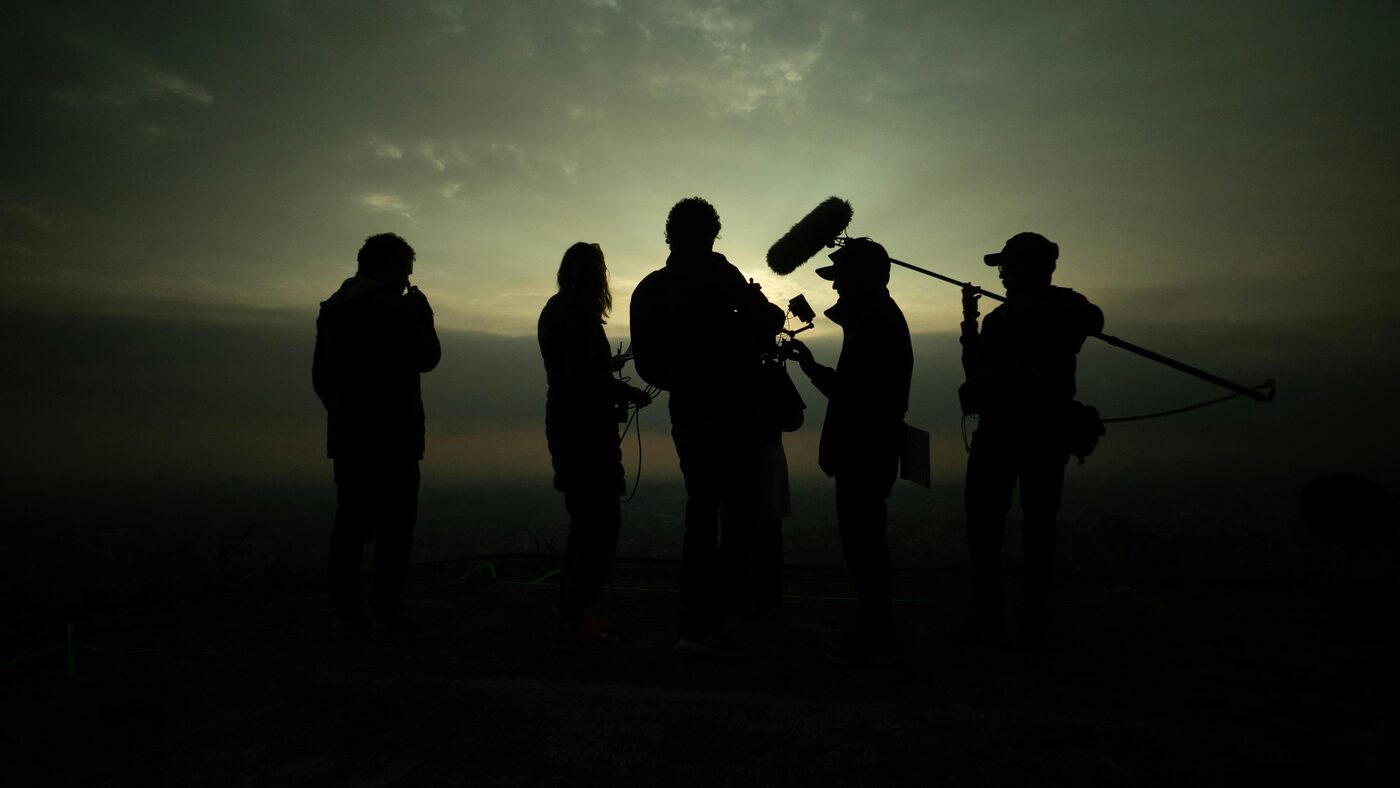 Equipa de produção audiovisual a gravar no exterior, ao pôr do sol