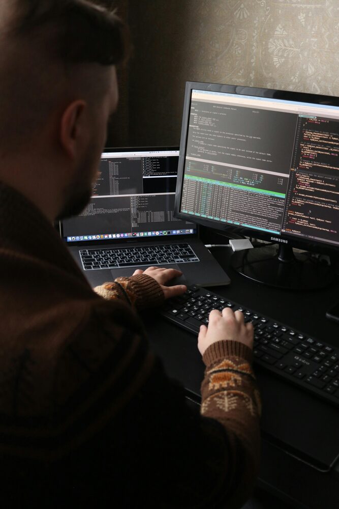 Aluno a programar num posto de trabalho com vários ecrãs